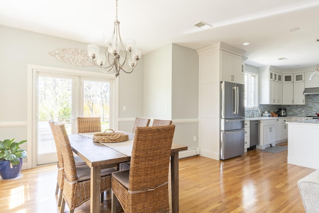 331 Riverview Dr, Chatham, MA 02633 - dining space featuring a baseboard radiator, a chandelier, and light wood-style floors