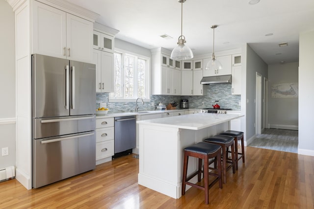 331 Riverview Dr, Chatham, MA 02633 - kitchen featuring appliances with stainless steel finishes, under cabinet range hood, tasteful backsplash, and light wood-style floors
