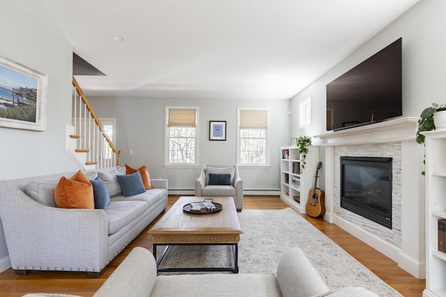 331 Riverview Dr, Chatham, MA 02633 - living room with a baseboard heating unit, a baseboard radiator, a glass covered fireplace, stairway, and wood finished floors
