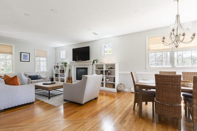 331 Riverview Dr, Chatham, MA 02633 - living room with a chandelier, a glass covered fireplace, and light wood-type flooring