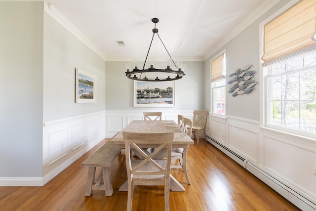 331 Riverview Dr, Chatham, MA 02633 - dining room featuring a baseboard heating unit, crown molding, light wood-style flooring, a wainscoted wall, and a decorative wall