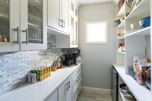 331 Riverview Dr, Chatham, MA 02633 - kitchen with backsplash, wood finished floors, white cabinets, glass insert cabinets, and baseboards