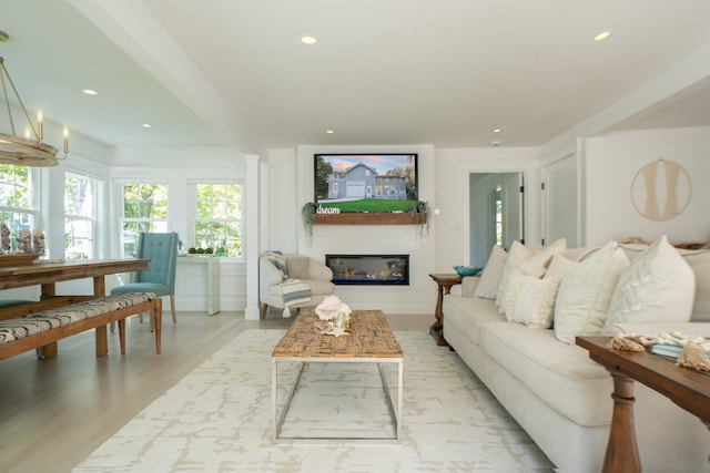 living area with light wood-style floors, recessed lighting, and a glass covered fireplace