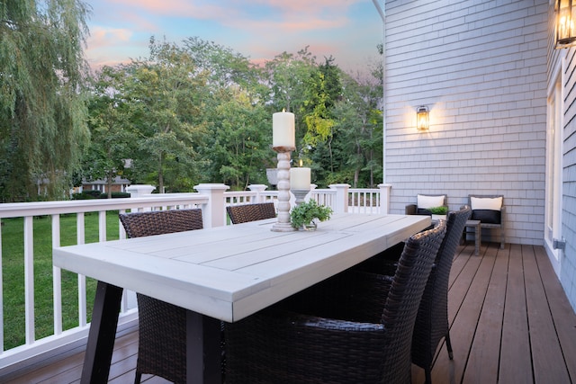 wooden terrace featuring outdoor dining area and a yard