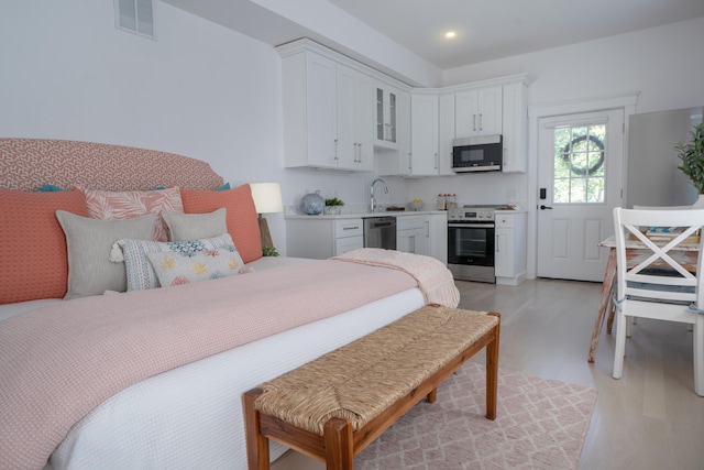 bedroom featuring light wood-style floors, visible vents, a sink, and recessed lighting