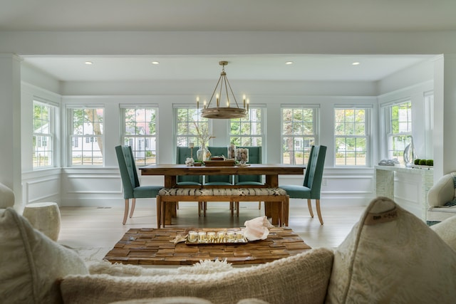 dining space featuring a chandelier, a decorative wall, wood finished floors, and recessed lighting