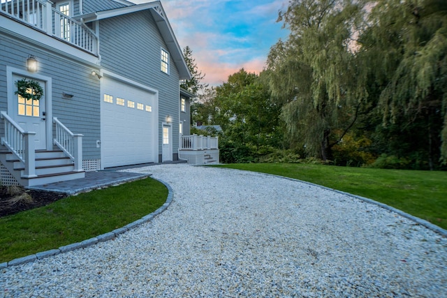 view of side of home featuring a yard, gravel driveway, and a balcony