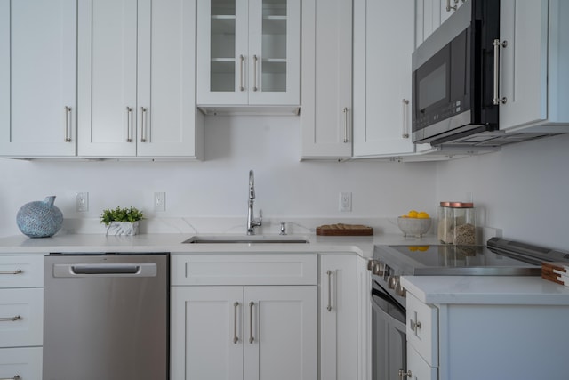 kitchen featuring appliances with stainless steel finishes, a sink, and white cabinetry