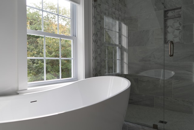 bathroom with a shower stall and a freestanding bath