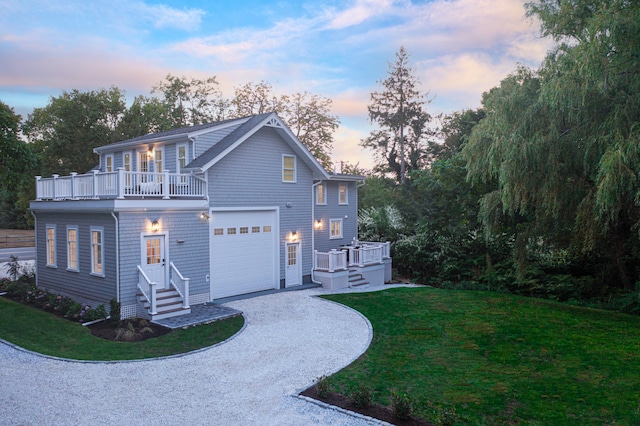 view of front of home featuring driveway, a lawn, an attached garage, and a balcony