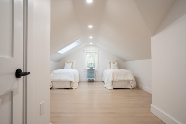 bedroom with light wood-style floors, vaulted ceiling with skylight, baseboards, and recessed lighting