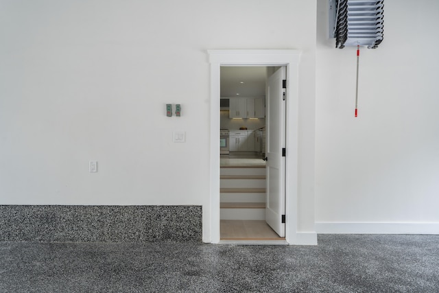 stairway featuring speckled floor and baseboards