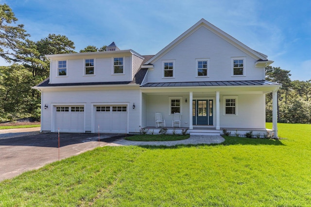 view of front of home with covered porch, a front yard, a standing seam roof, a garage, and driveway