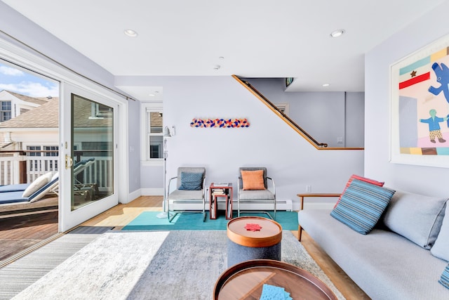 living area with a baseboard heating unit, recessed lighting, wood finished floors, and baseboards