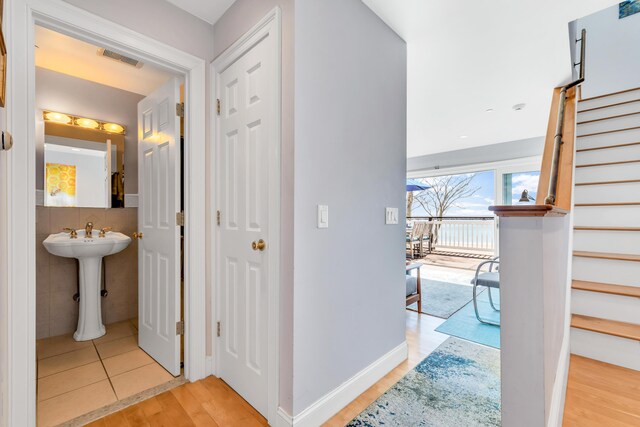 corridor featuring stairway, wood finished floors, visible vents, and a sink