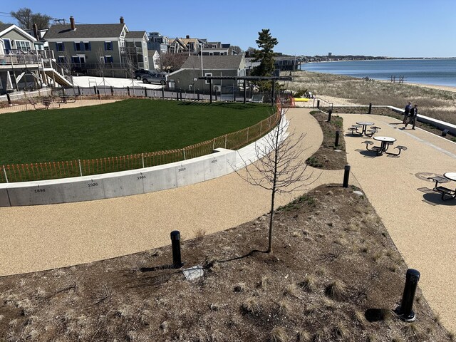 view of community featuring fence, a lawn, a water view, and a residential view