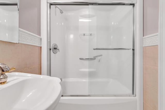 bathroom featuring a shower with shower door and a sink