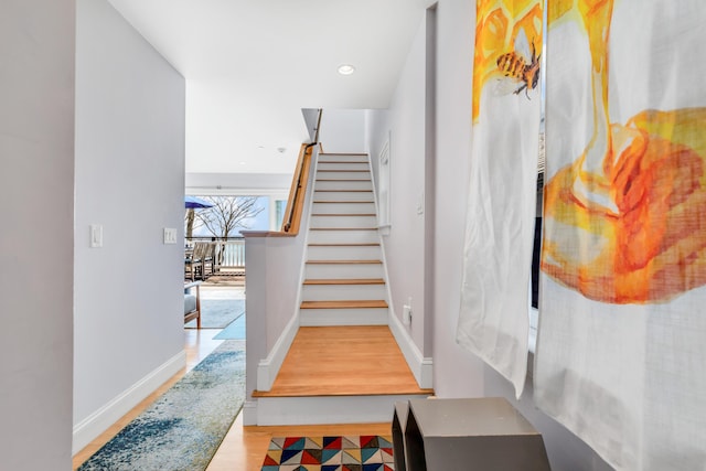 staircase featuring wood finished floors and baseboards