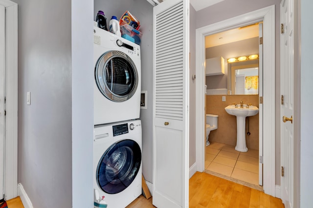 laundry area featuring stacked washer / dryer, light wood-style flooring, laundry area, and a sink
