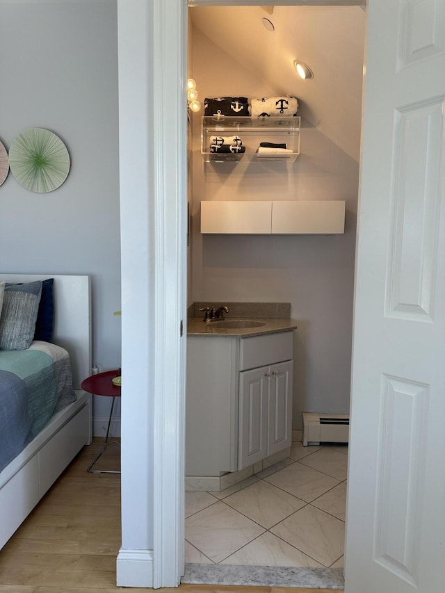 bathroom with a baseboard heating unit, wood finished floors, and vanity