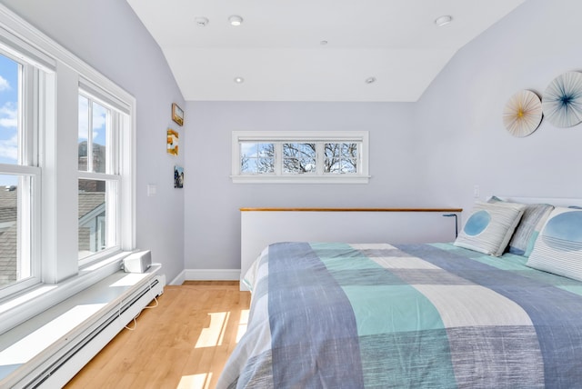 bedroom featuring a baseboard radiator, vaulted ceiling, and multiple windows