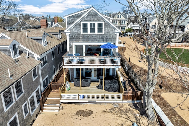 back of property featuring a deck, a jacuzzi, and a residential view