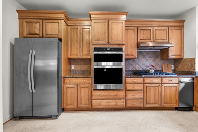 kitchen with appliances with stainless steel finishes, dark stone countertops, and backsplash