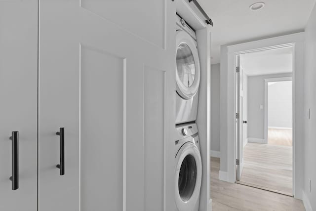 6 Januit St, Sandwich, MA 02563 - laundry area with stacked washer and clothes dryer, light wood-style floors, baseboards, and a barn door