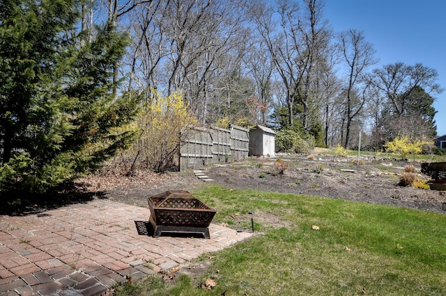 view of yard featuring a fire pit, a patio, a storage shed, and an outdoor structure