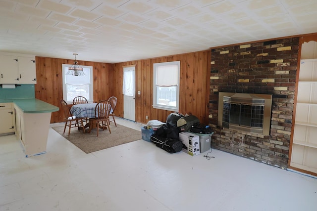 dining space featuring a brick fireplace and wood walls