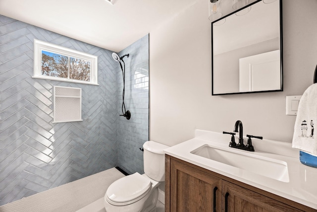 bathroom featuring a tile shower, toilet, and vanity