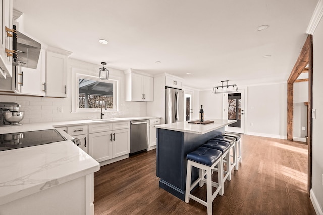 kitchen with white cabinetry, stainless steel appliances, a center island, and sink