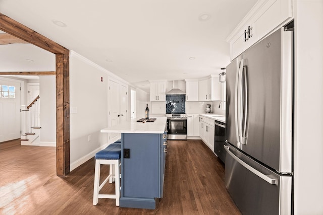 kitchen featuring white cabinetry, wall chimney range hood, stainless steel appliances, a center island with sink, and a breakfast bar area