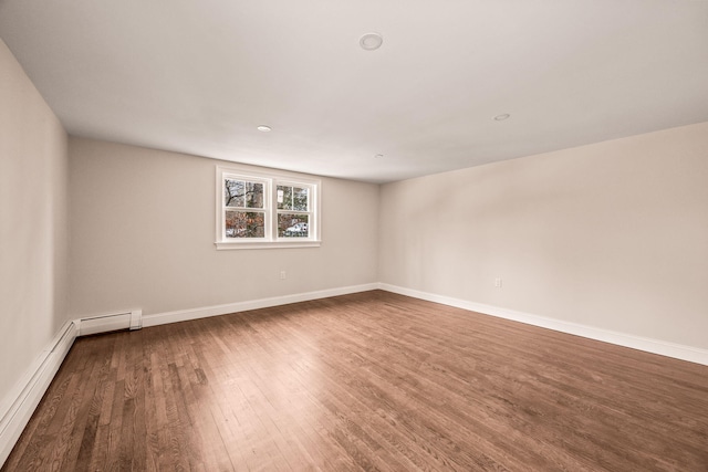 unfurnished room featuring hardwood / wood-style floors and a baseboard heating unit