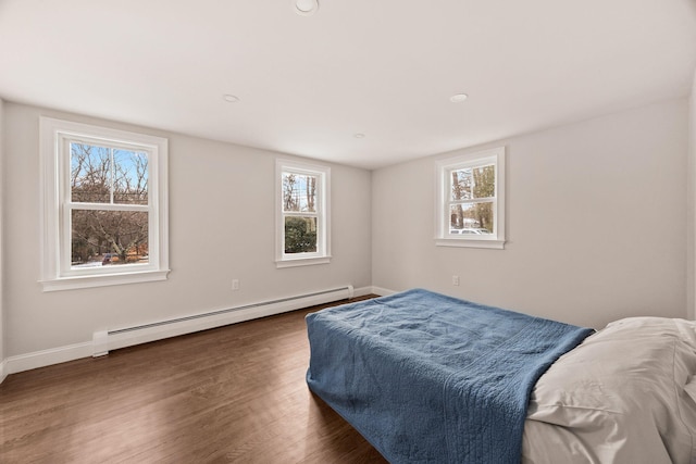 bedroom with baseboard heating, multiple windows, and dark wood-type flooring