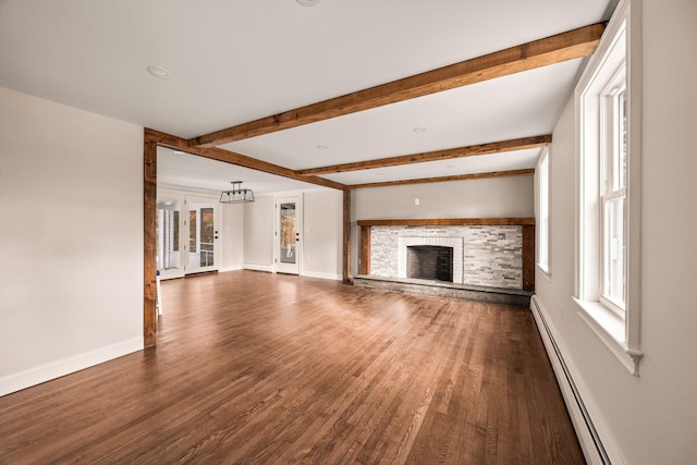 unfurnished living room featuring baseboard heating, a wealth of natural light, dark hardwood / wood-style flooring, and beamed ceiling