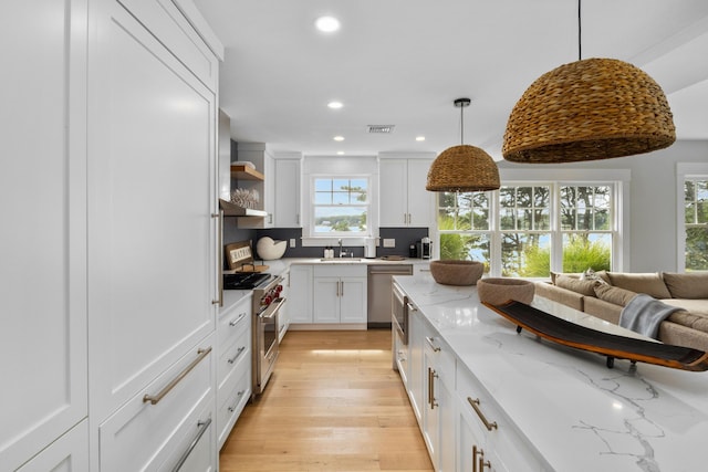 kitchen featuring white cabinets, stainless steel appliances, tasteful backsplash, plenty of natural light, and light stone counters