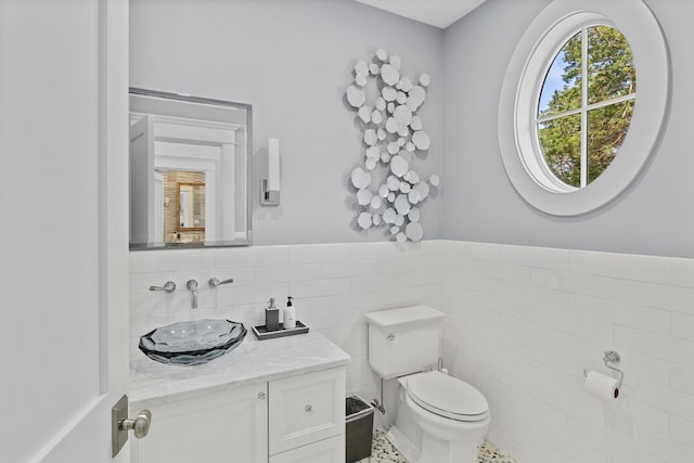 bathroom with vanity, toilet, tile walls, and tile patterned flooring