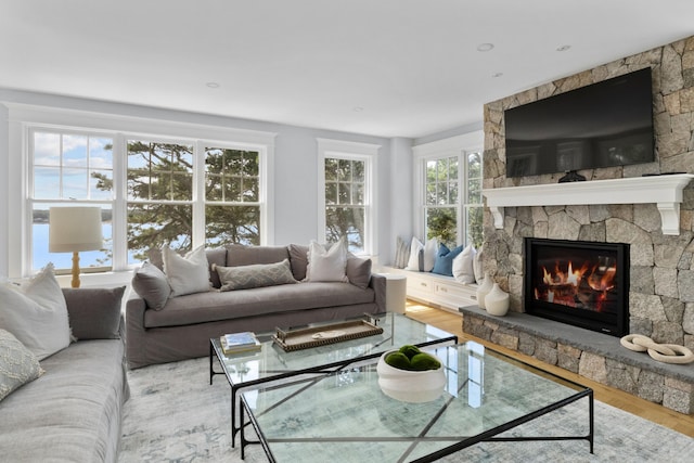 living room featuring light wood-type flooring, plenty of natural light, and a fireplace