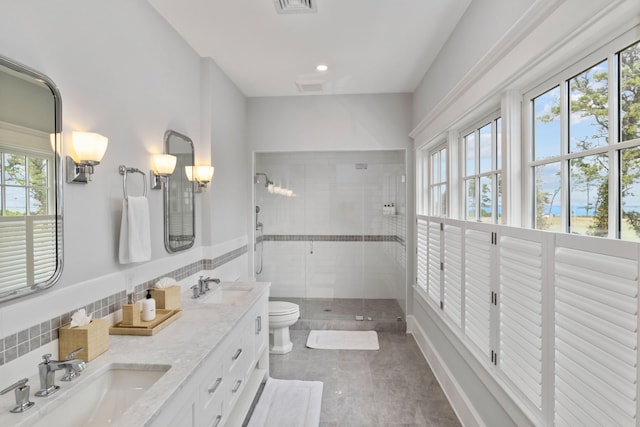 bathroom with toilet, a shower with door, vanity, and a healthy amount of sunlight