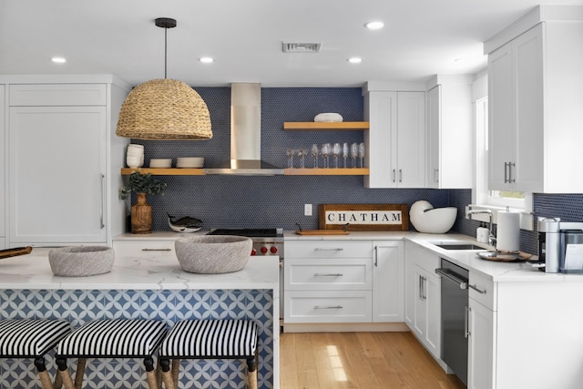 kitchen with decorative light fixtures, decorative backsplash, wall chimney range hood, and white cabinetry