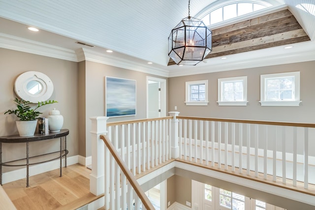 hall featuring a healthy amount of sunlight, ornamental molding, and light hardwood / wood-style floors