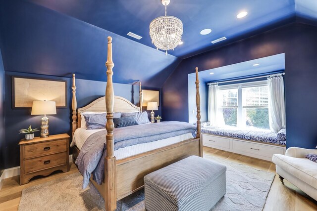 bedroom with light hardwood / wood-style floors, lofted ceiling, and an inviting chandelier