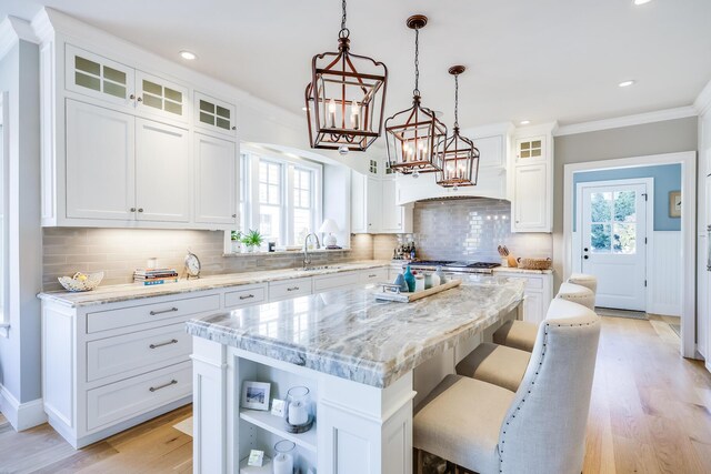 kitchen featuring pendant lighting, white cabinetry, ornamental molding, and a kitchen island