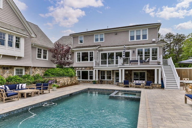 rear view of property with outdoor lounge area, stairs, a patio area, and stone siding