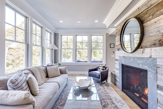 living room with light wood-type flooring, a high end fireplace, and ornamental molding