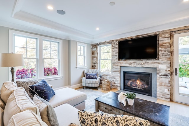 living room featuring light hardwood / wood-style flooring, ornamental molding, and a stone fireplace