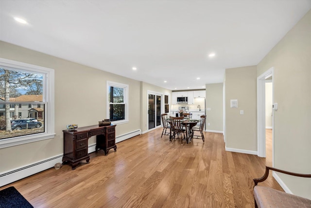 dining room with a baseboard heating unit, recessed lighting, baseboards, and light wood finished floors