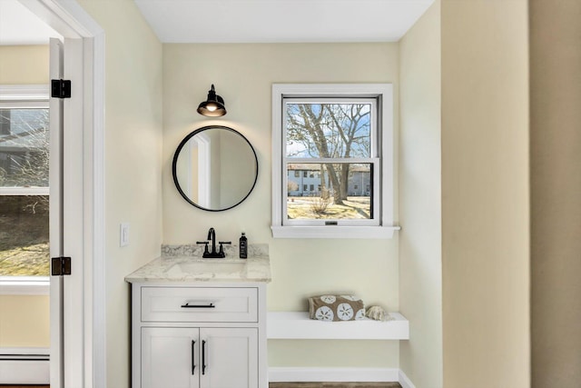 bathroom featuring vanity, a baseboard heating unit, and baseboards