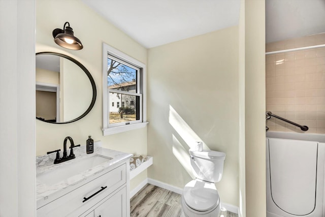 full bathroom with toilet, wood finished floors, a shower, baseboards, and vanity